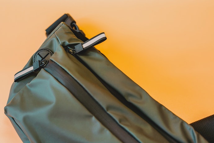 Cari tas selempang dengan penutup yang tidak mudah kemasukan air, seperti ritsleting kedap air