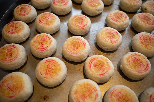 Kue bulan warna putih: Bentuknya pipih dan bertuliskan tinta merah